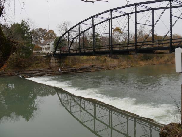 Old historic bridge reflected in the waters of War Eagle river on a cold autumn morning at Benton County, Arkansas.