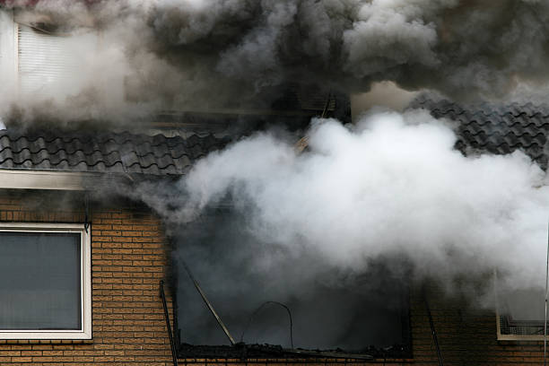 Big fumes of smoke coming out of the second floor of a residential building.