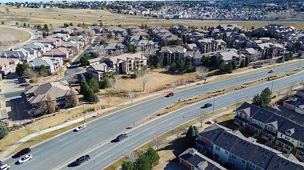 Central roadway near Ponderosa Trail divides housing clusters and golf course edges stretching toward distant ridges. Light roofs, open fairways, soft vegetation winter landscape in CO. USA