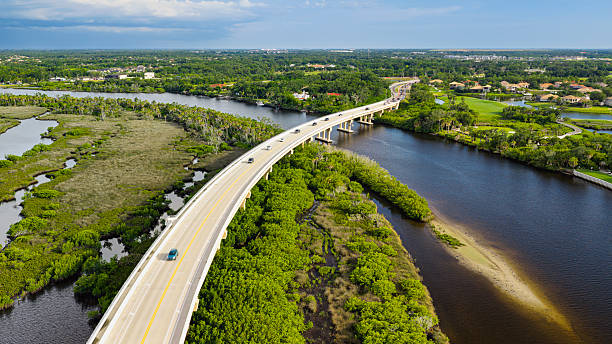 An aerial view of the Fort Hamer Bridge over the Manatee River in Bradenton, Florida. Afternoon rain showers fill the dark sky in the distance.