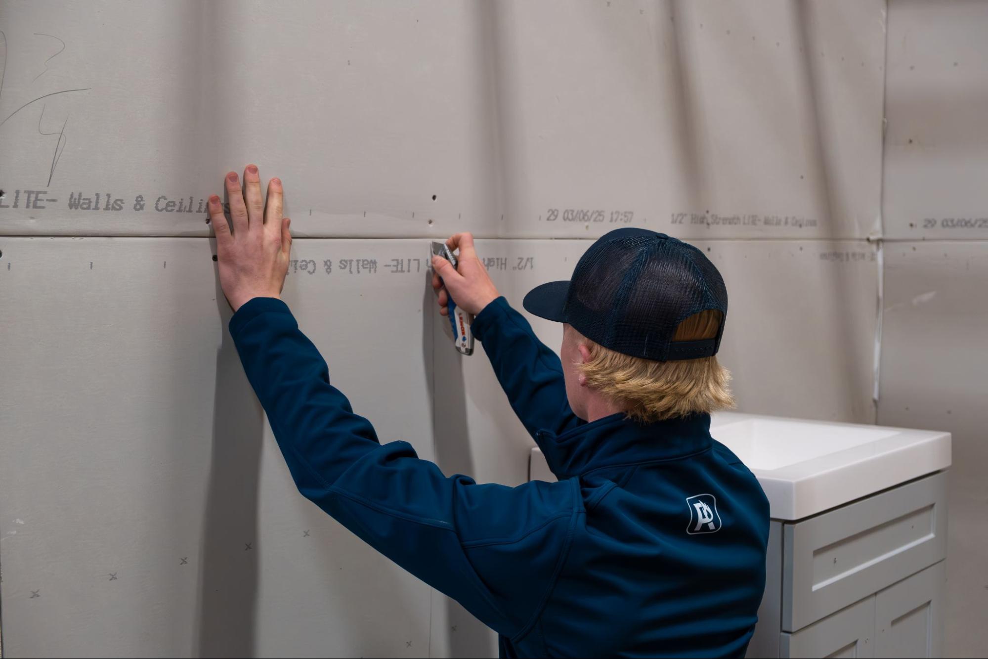 man measuring damage in house