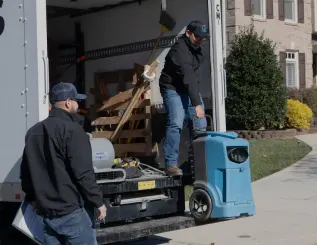 two restoration workers unloading a truck