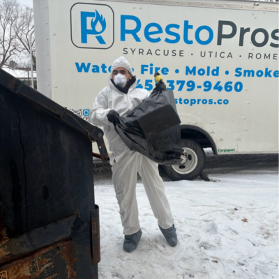 Man in front of Syracuse-Utica-Rome RestoPros truck removing waste