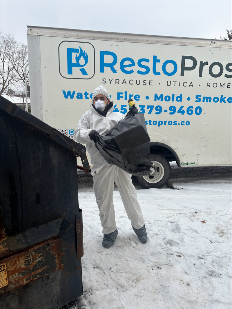 Man in front of Syracuse-Utica-Rome RestoPros truck removing waste