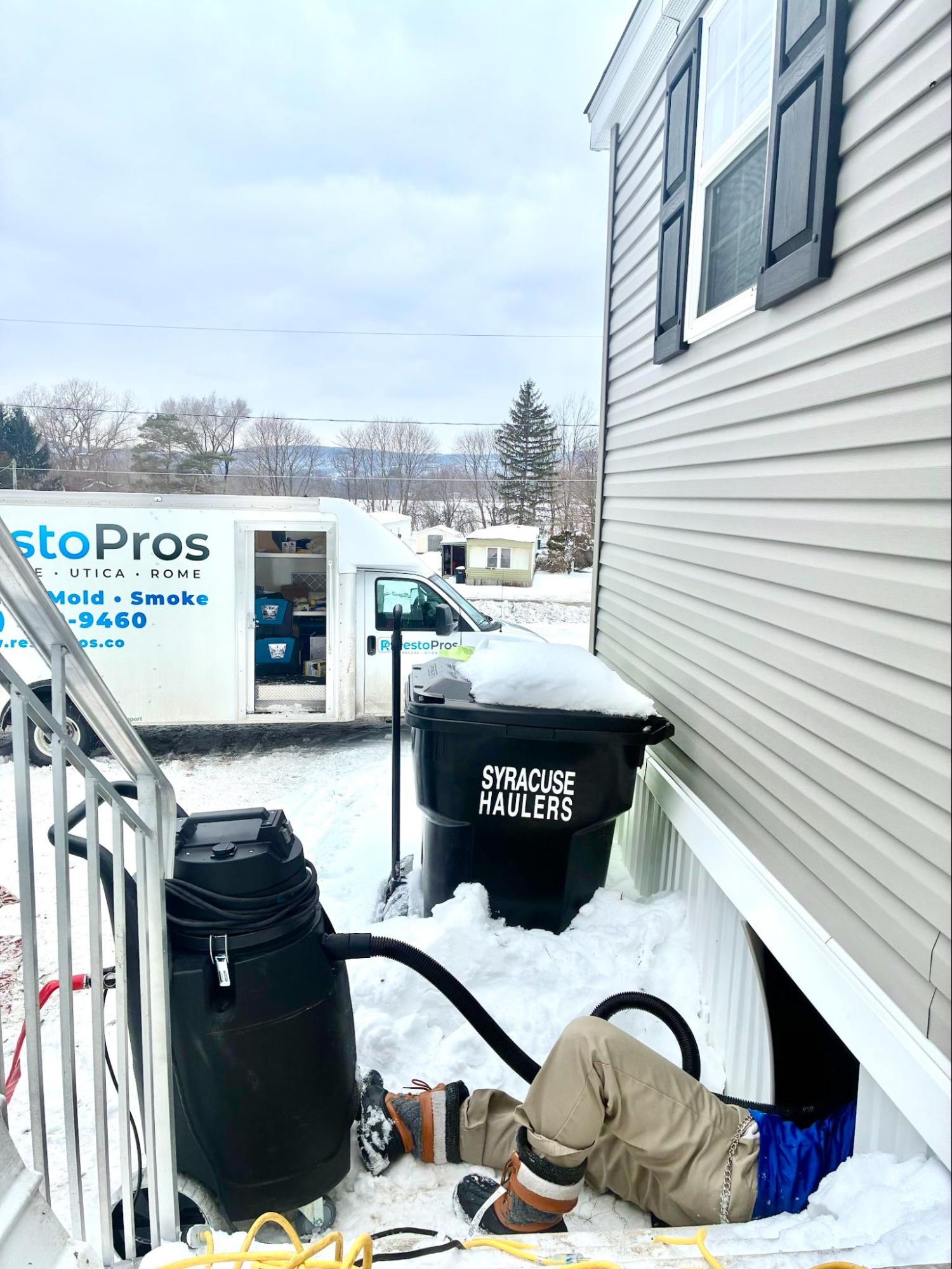 Man under house for restoration in the snow