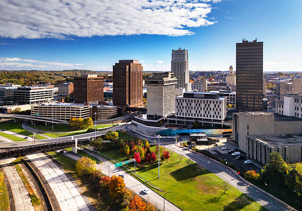 Aerial of the Downtown Akron skyline during autumn, with a highway with trees and a lawn in the foreground.