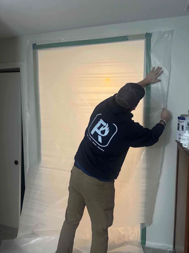 Restopros worker taping a tarp onto a doorway