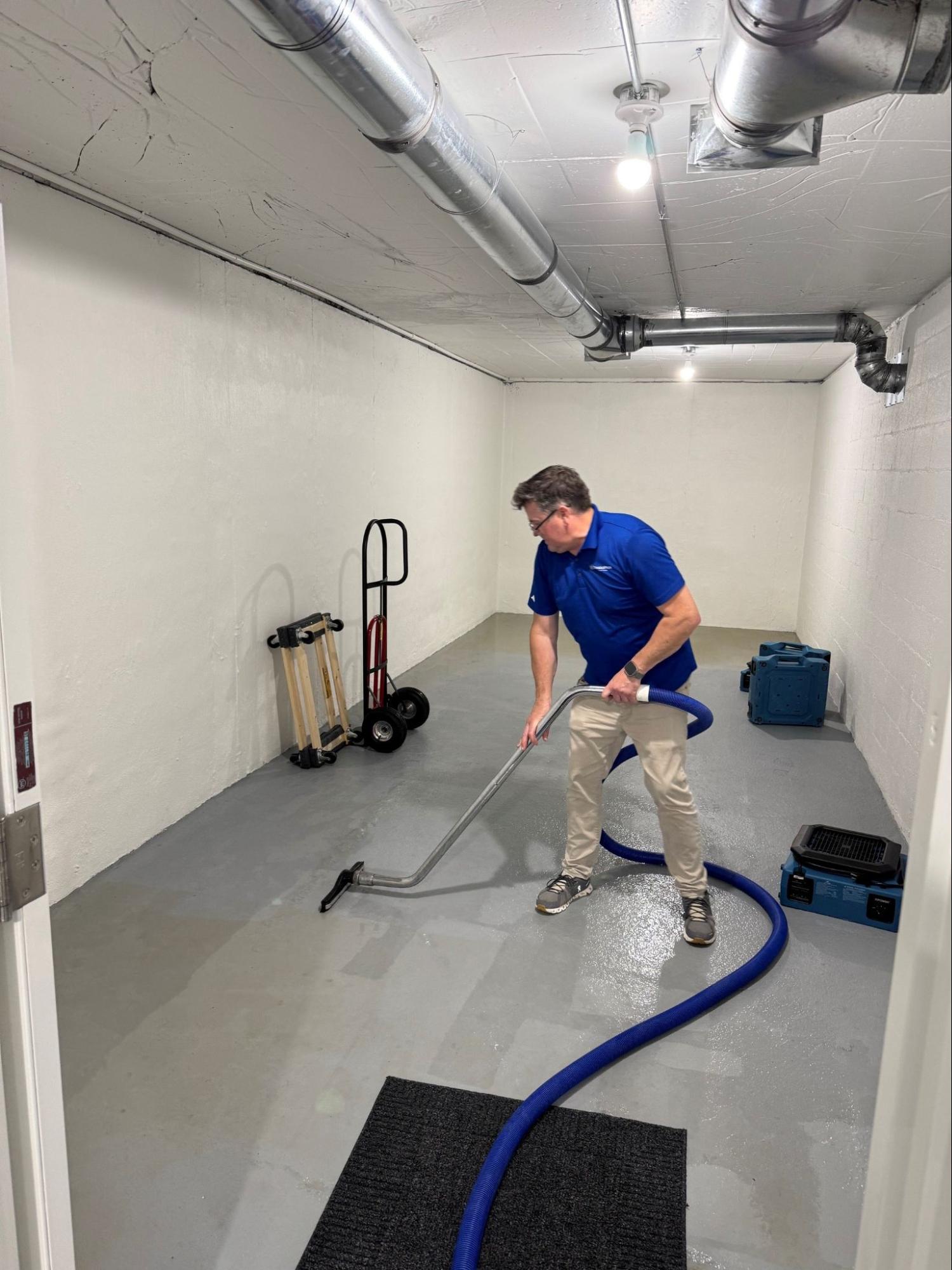 RestoPros technician extracting water from a flooded basement floor.