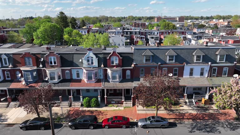 Historic row houses with distinct architectural details, tree-lined streets, and parked cars. Aerial truck shot in American city during spring.