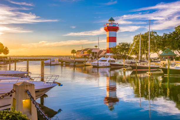 Harbour Town lighthouse and marina at sunset on Hilton Head Island with boats docked in still water