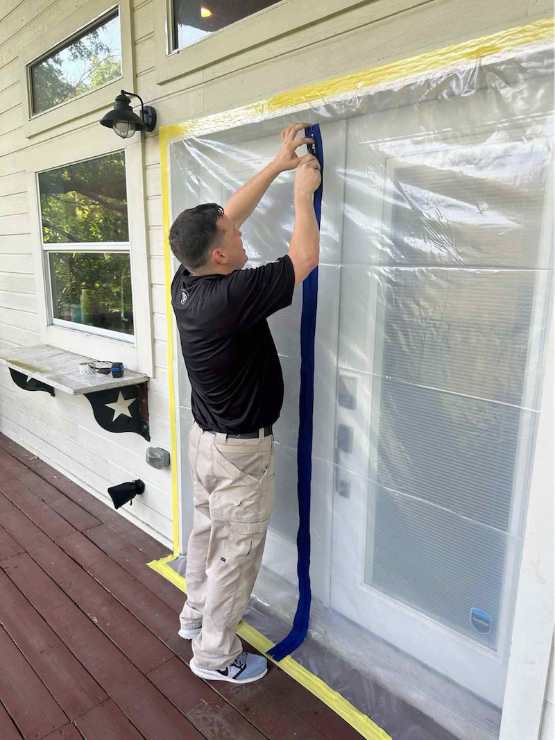 Man placing plastic over door for home restoration