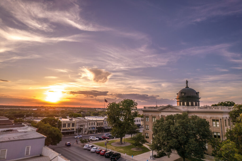 architecture-of-courthouse-in-georgetown-texas-with-street-view-cars-greenery-at-sunset