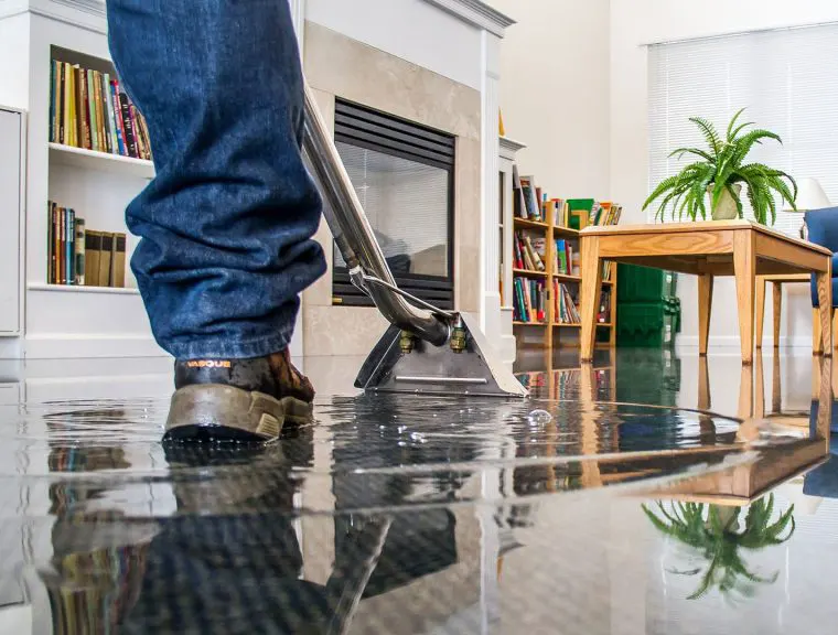 Person with foot in water damaged living room