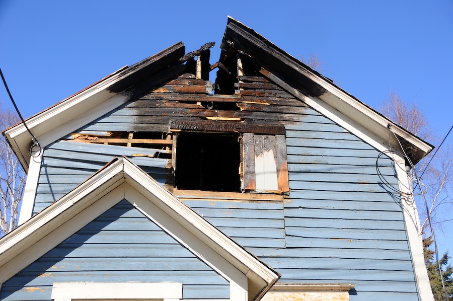 Blue wooden home with the roof burned away