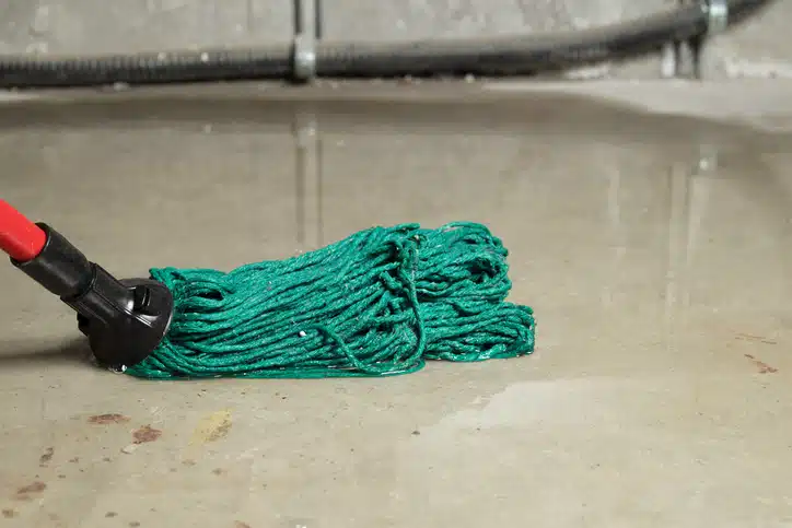 Deep water on floor. Close up of mop in water with defocused large electrical cable. Water damage from rain, snowmelt or pipe burst. Selective focus.