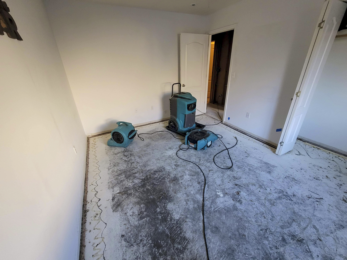 Water Damaged bedroom with carpet removed and air movers with a dehumidifier for drying