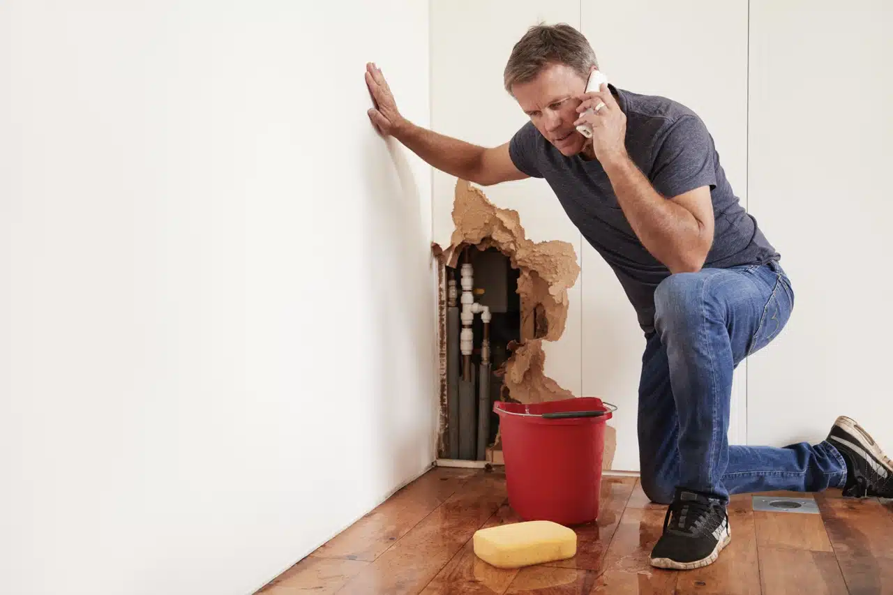 middle-aged-man-with-a-burst-water-pipe-phoning-for-help