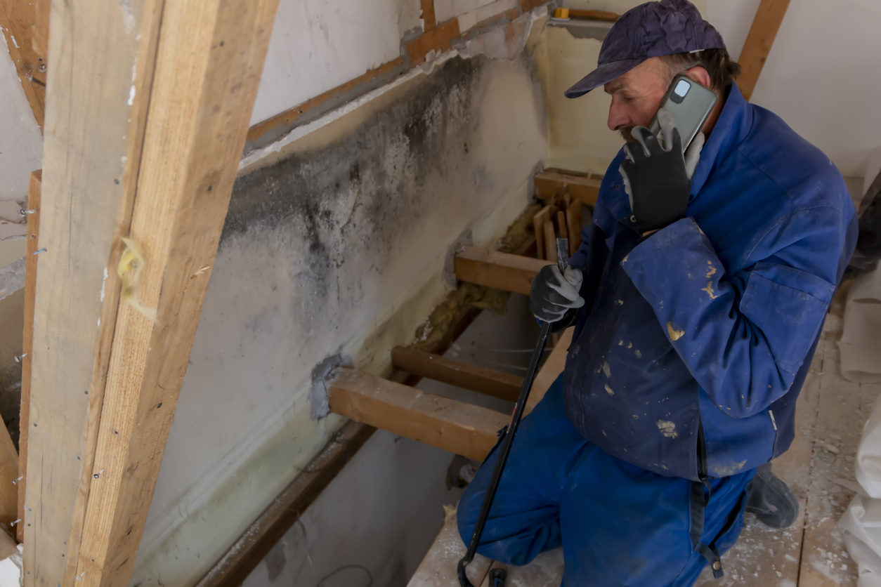 A worker is holding a phone and talking while working on a house renovation.