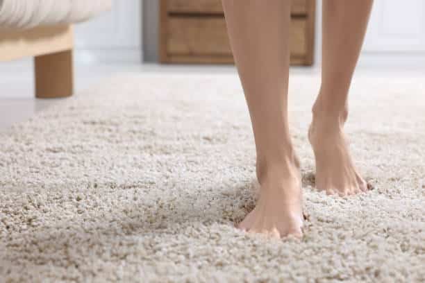Woman walking on soft light brown carpet at home, closeup