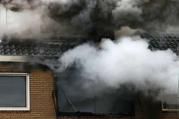 Big fumes of smoke coming out of the second floor of a residential building.
