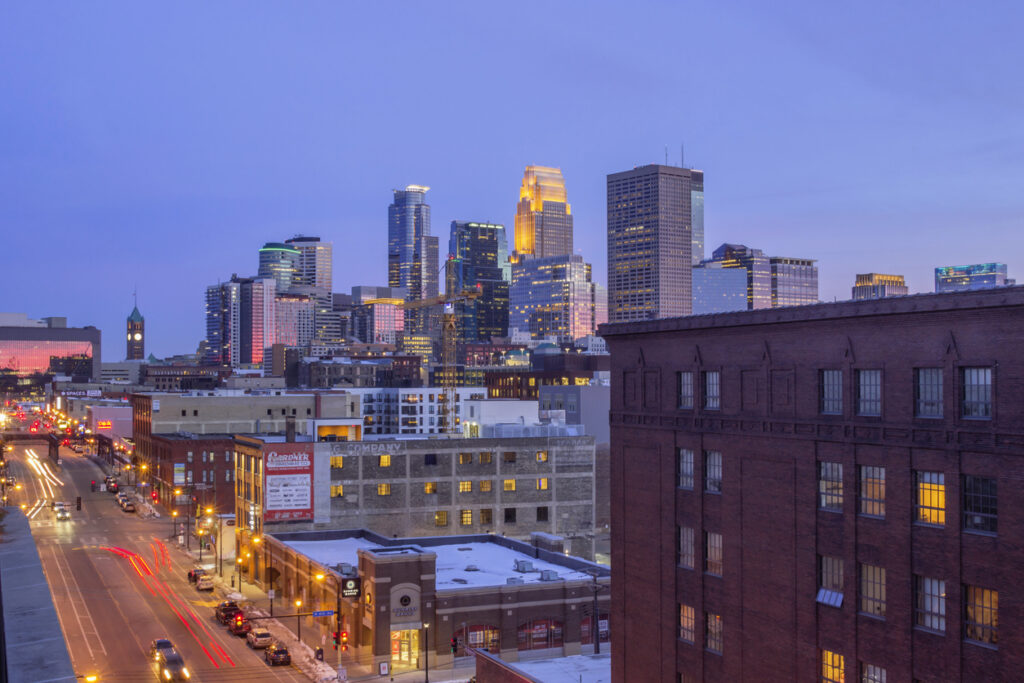 A Wide Angle Shot of Downtown Minneapolis Reflecting Pink Dusk Light as North Loop Traffic Passes in the Foreground